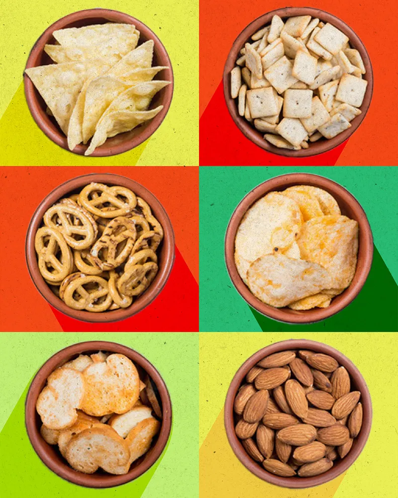 A grid of bowls of snacks, from walnuts and pretzels to popcorn and pistachios, on bright color blocks.